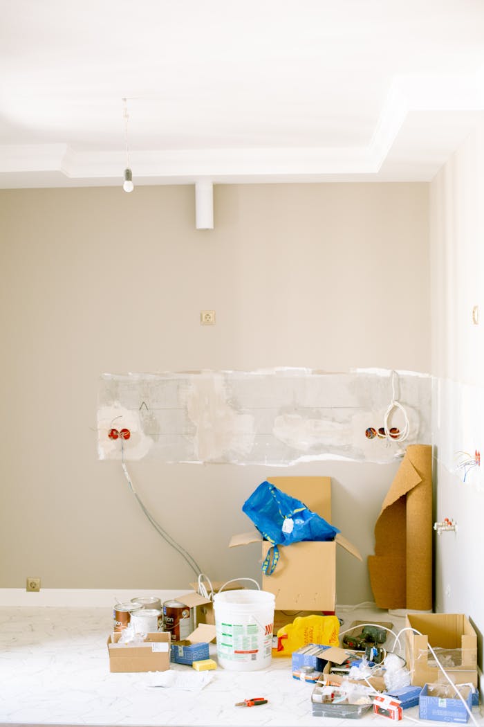 An indoor scene showing a messy home renovation project with tools, paint, and materials scattered around.